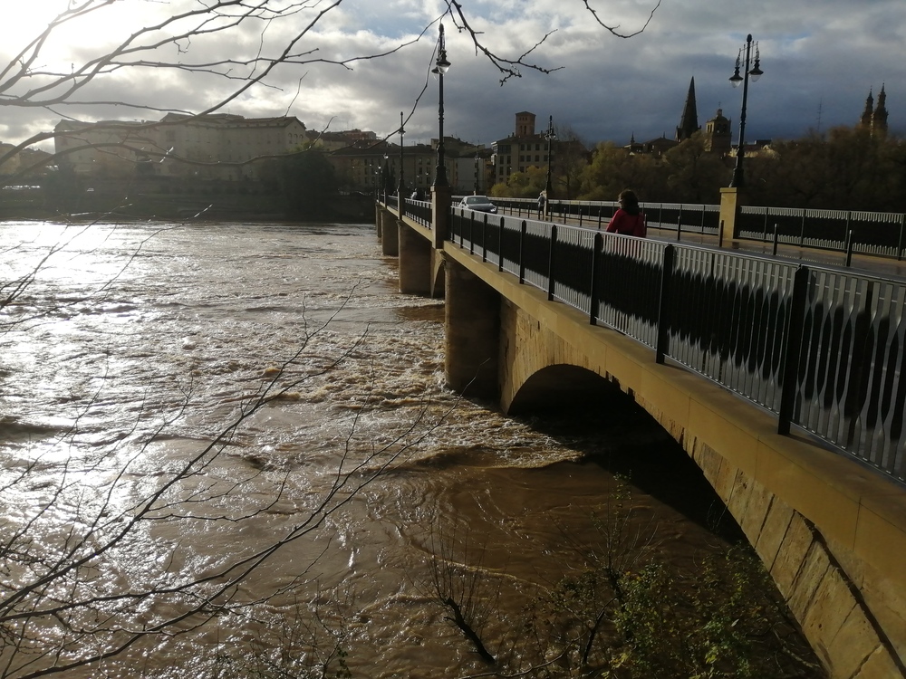 La riada ha sido de tal magnitud que el agua apenas deja ver los ojos del puente de piedra de Logroño.  / EL DÍA